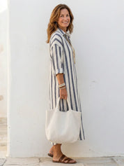 Detail van gestreepte midi shirtjurk met knoopsluiting en lange mouwen